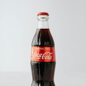 Close-up of a classic Coca-Cola bottle with red label against a plain white background.